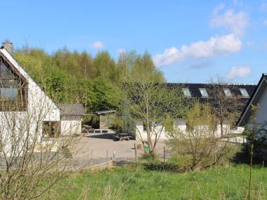 Fredensgård, en firlænget, hvid gård, set fra en bakketop